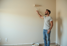 Homme en vêtements décontractés appliquant une sous-couche sur un mur intérieur