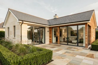 Maison en L moderne à 4 chambres avec façade en enduit clair et bardage bois, orientée plein sud pour optimiser l'apport de lumière naturelle